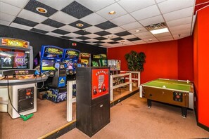 Una habitación con máquinas de videojuegos, una mesa de fútbol de mesa y una pared roja.