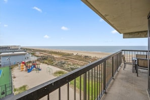 Un balcón con vista a una playa y un parque infantil.