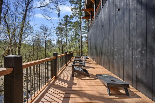 A wooden deck with benches and a railing overlooking a forested area.