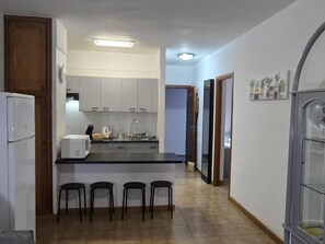 A kitchen with white cabinets, a black countertop, and four black stools.