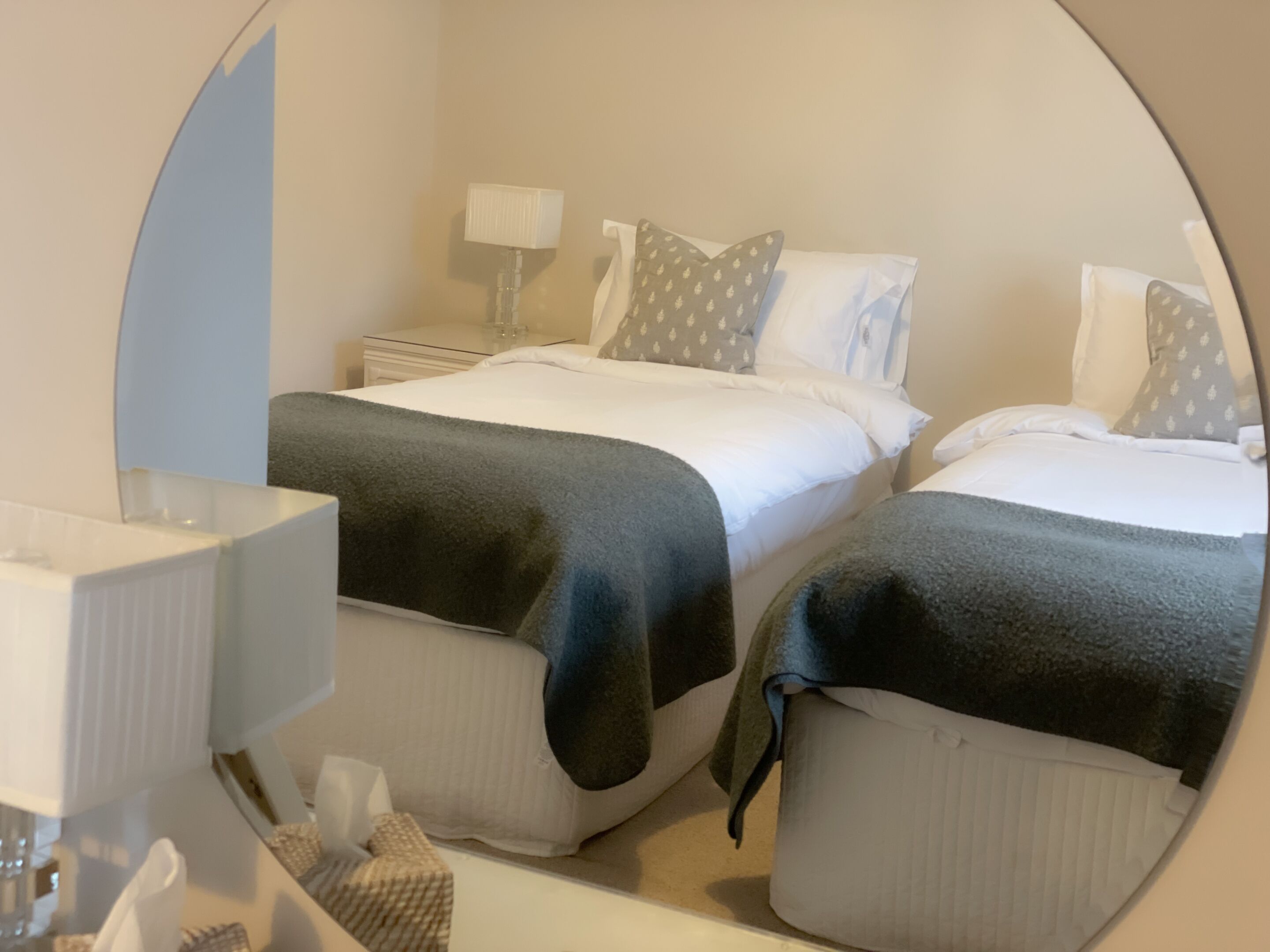 Ein Hotelzimmer mit zwei Betten, einem Nachttisch, einer Lampe und einem Spiegel.