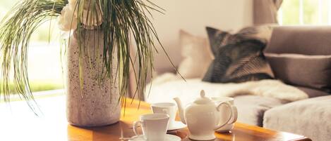 A cozy living room with a coffee table holding a plant, a teapot, and cups.