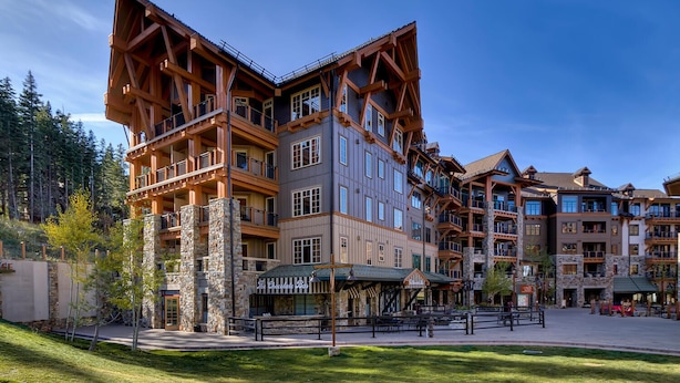Un hotel a più piani con uno stile architettonico rustico, caratterizzato da balconi e colonne in pietra.