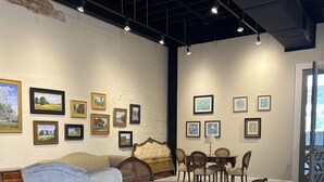 A dining area with a round table and chairs, a sofa, and a wall with framed pictures. - 4 Luxury Suites in a beautifully restored historic building in Buffalo, Texas.  (Buffalo)