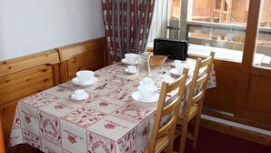 A dining table set with white dishes and a pitcher, wooden chairs, and a patterned tablecloth. - Ski-in/ski-out & foot of the slopes, 1st floor, view ski slopes, balcony, tv, 32m², Val Thorens (Val Thorens)