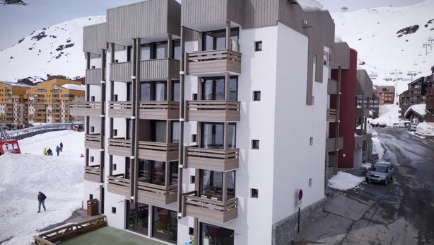 A multi-story building with balconies, a ski lift in the background, and a snowy mountain. - Ski-in/ski-out & foot of the slopes, 1st floor, view ski slopes, balcony, tv, 32m², Val Thorens (Val Thorens)