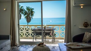Una stanza con una porta scorrevole in vetro che dà su un balcone con vista sull'oceano e palme.