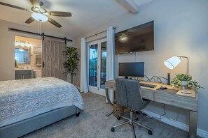 A bedroom with a bed, desk, computer, and ceiling fan.