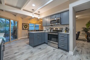 A modern kitchen with grey cabinetry, stainless steel appliances, and a large island.