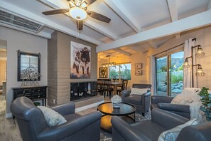 A spacious living room with leather sofas, a fireplace, and a dining area.