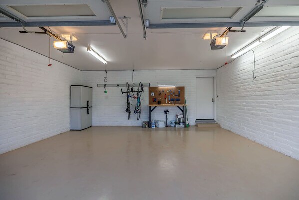 A spacious room with white brick walls, a pegboard with tools, and a bicycle.