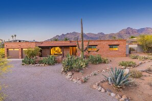 A residential property with a brick exterior, a garage, and a landscaped garden with cacti and agave plants.