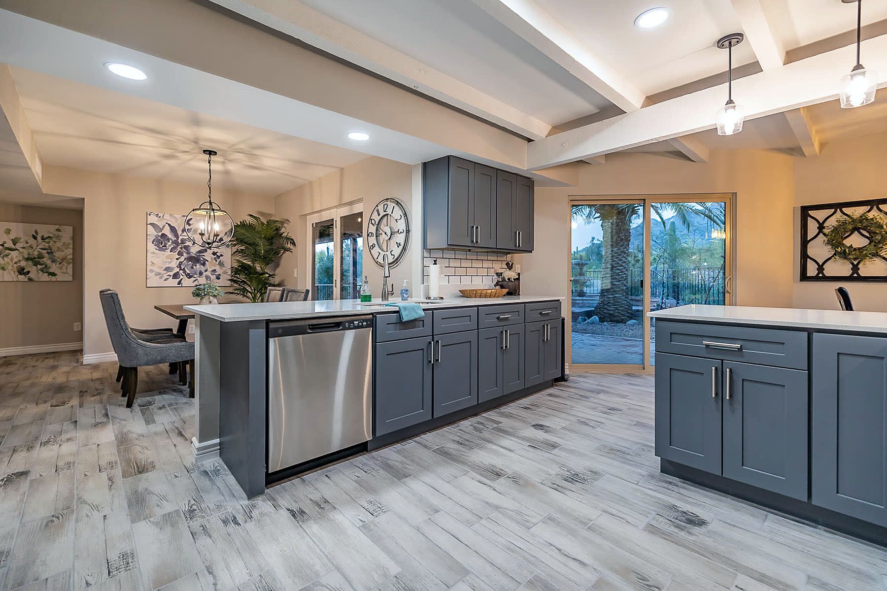A modern kitchen with grey cabinetry, stainless steel appliances, and a central island.