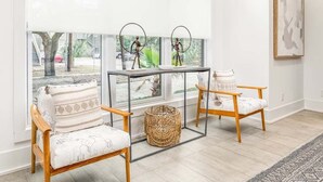 A modern living room with a glass partition, two chairs, a small table, and a woven basket. - Savannah Jetsetter | Pet Friendly, Luxury Townhome, Historic Savannah (Savannah)