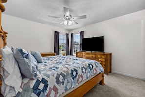 A bedroom with a bed, a ceiling fan, a dresser, and a TV. - Family Size Beach Condo-Sleeps 10/ min to the Surfside Beach! (Myrtle Beach)