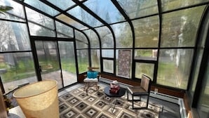 Un conservatorio con piso de diseño geométrico, una lámpara grande y dos sillones.