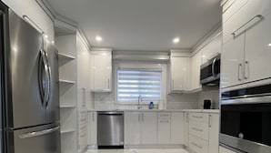 Una cocina moderna con armarios blancos, electrodomésticos de acero inoxidable y suelo de mármol.