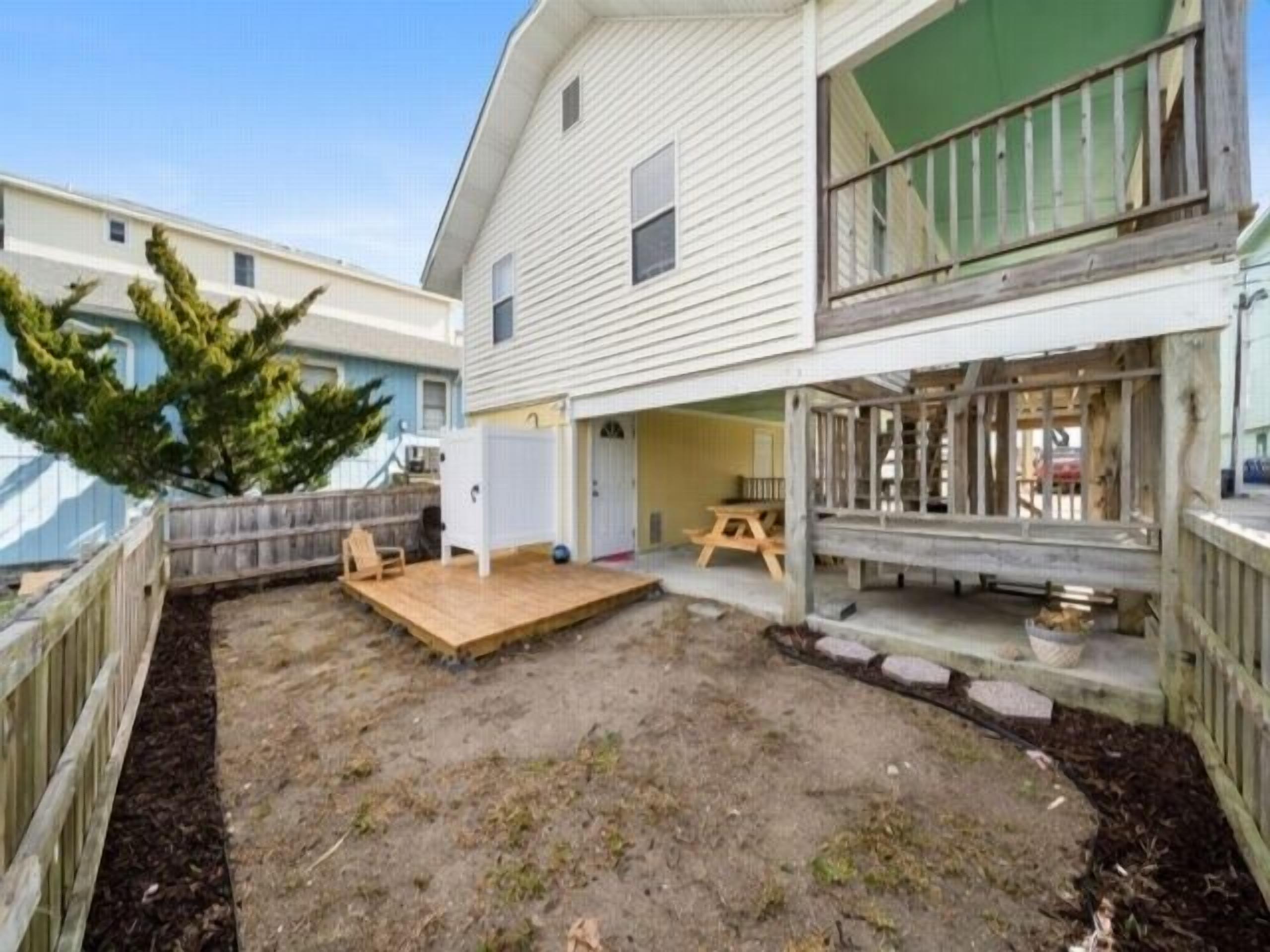 A two-story house with a fenced backyard, a wooden deck, and a small patio area.