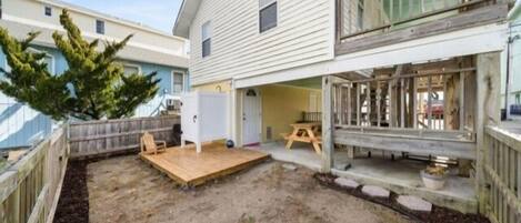 A two-story house with a fenced backyard, a wooden deck, and a small patio area.