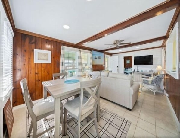 A spacious living area with a dining table, chairs, a sofa, and a TV.