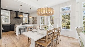 Een moderne keuken met een centraal eiland, houten vloeren en grote ramen met uitzicht op de omgeving.