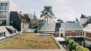 Un jardin sur le toit offrant une vue sur des bâtiments traditionnels et, au loin, sur le clocher d’une église.