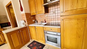 A kitchen with wooden cabinets, a stainless steel oven, and a tiled backsplash. - Balcony & serenity: peak views (Le Monêtier-les-Bains)