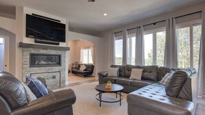 A spacious living room with leather sofas, a fireplace, and large windows. - Upper Unit: Raspberry Mountain Family Farmhouse (Monument)
