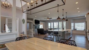 A spacious kitchen with a central island, dining area with a large wooden table, and a cozy seating area with a sofa and chairs. - Upper Unit: Raspberry Mountain Family Farmhouse (Monument)