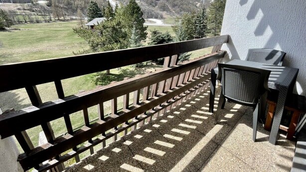 A balcony with a view of a mountainous landscape, a table, and a chair. - Nice 28m² Comfort In The Heart La Salle Les Alpes (La Salle-les-Alpes)