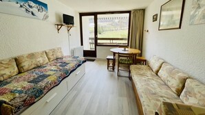 A bedroom with a bed, a sofa, a small table, and a window with a view of the outdoors. - Nice 28m² Comfort In The Heart La Salle Les Alpes (La Salle-les-Alpes)