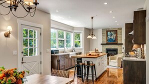 Una cocina moderna con una isla central, suelo de madera y un comedor con mesa y sillas.