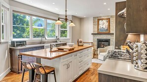 Una cocina moderna con una isla grande, armarios blancos y una chimenea.