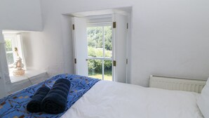 Een slaapkamer met een bed, een raam en een radiator.