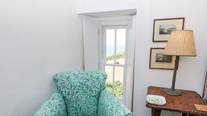 Een hoekappartement met een gestreept fauteuil, een tafel met een lamp en lijstwerken aan de muur.