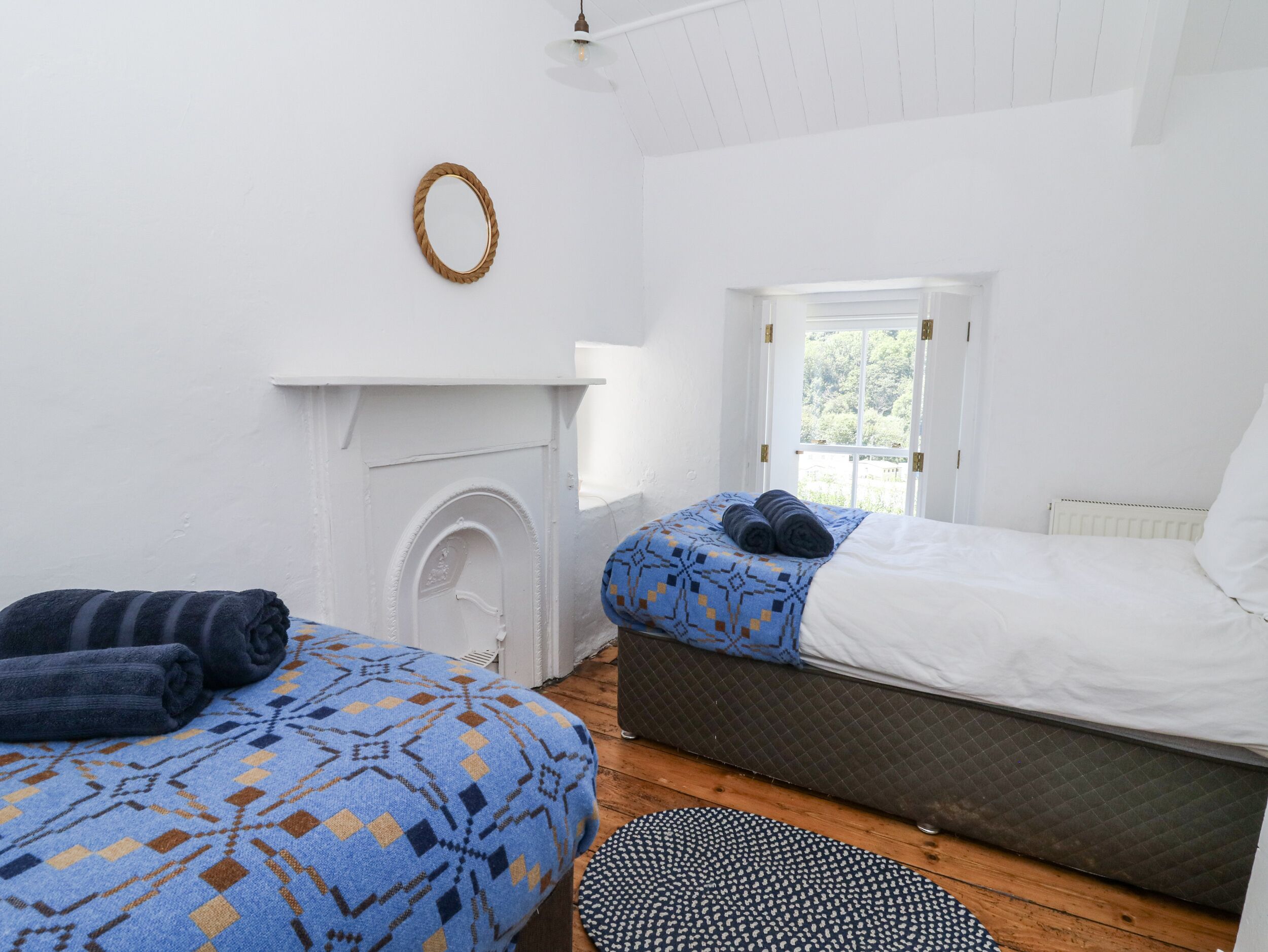 A bedroom with a bed, a window, a fireplace, and a small rug.