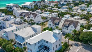 Zona residencial costera con edificios blancos, algunos con techos inclinados y otros planos, rodeada de palmeras.