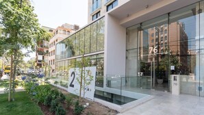 Un edificio moderno con amplios ventanales de vidrio, un jardín cuidado y vistas despejadas a la calle.