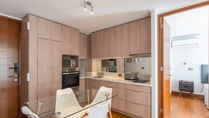 Una cocina moderna con armarios de madera, una mesa de comedor de vidrio y sillas blancas.