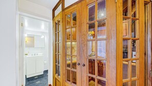 Un couloir avec des armoires en bois et une porte blanche donnant accès à une salle de bain.