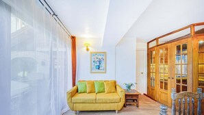 Un salon avec un canapé jaune, un meuble en bois et une table sur laquelle est posé un vase.