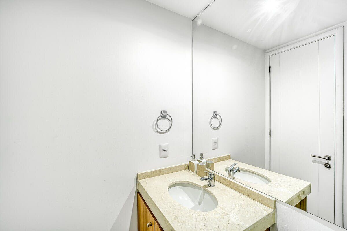 Une salle de bain avec deux lavabos, un miroir et une porte.