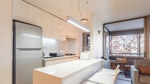 A modern kitchen with a large island, white cabinetry, and a built-in oven.