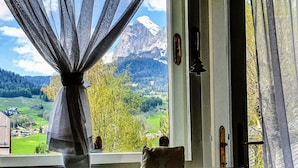 Ein Zimmer mit Blick auf eine Berglandschaft durch ein Fenster mit transparenten Vorhängen.