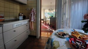 Keittiössä on liesi, kello ja ruokailutila, jossa on pöytä katettuna kahdelle.