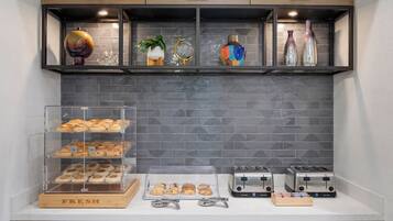 A kitchen counter with a bread display, two toasters, and a decorative shelf with various items.