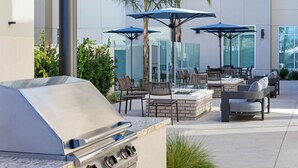 An outdoor patio with a built-in grill, seating area, and umbrellas. - Residence Inn by Marriott Chatsworth (Chatsworth)