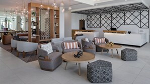 A modern lounge area with sofas, ottomans, and tables, a reception desk, and pendant lighting. - Residence Inn by Marriott Chatsworth (Chatsworth)