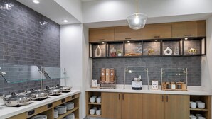 A modern kitchen with grey tiled backsplash, wooden cabinets, and a glass shelf displaying various kitchen items. - Residence Inn by Marriott Chatsworth (Chatsworth)