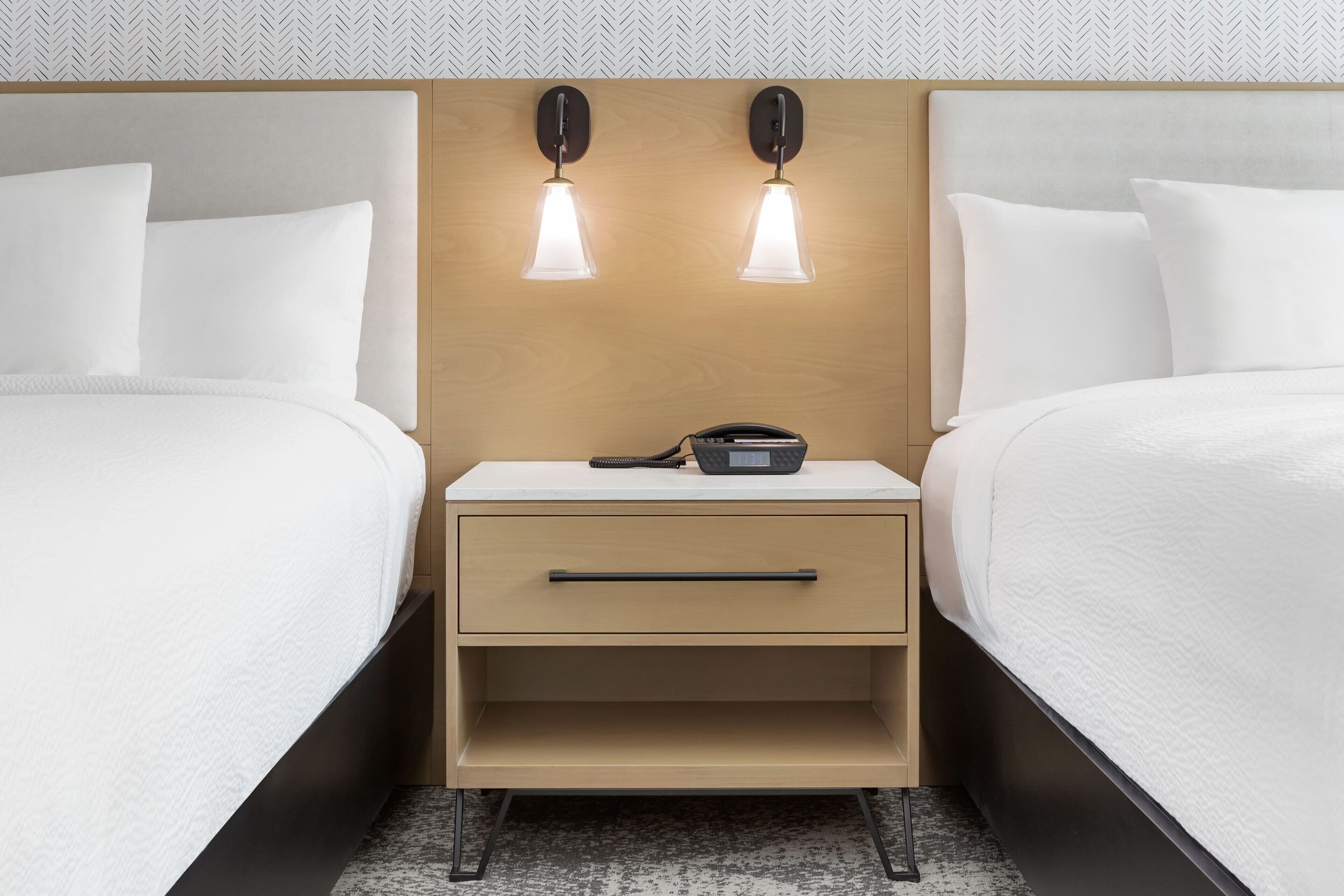 Ein Hotelzimmer mit zwei Betten, einem Nachttisch mit Lampe und einem Telefon.